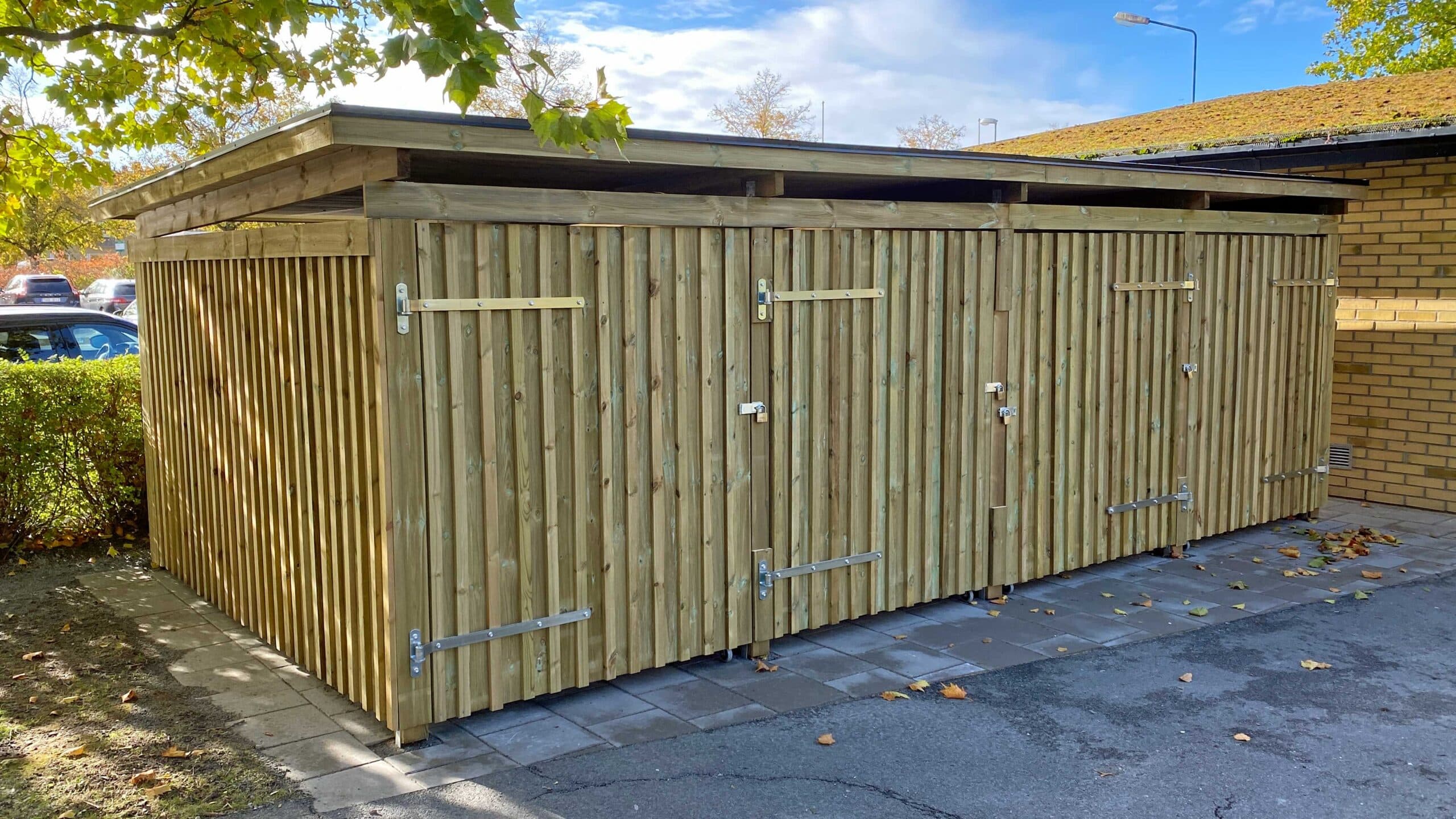 Skyddad träbyggnad med platser för lådcyklar.